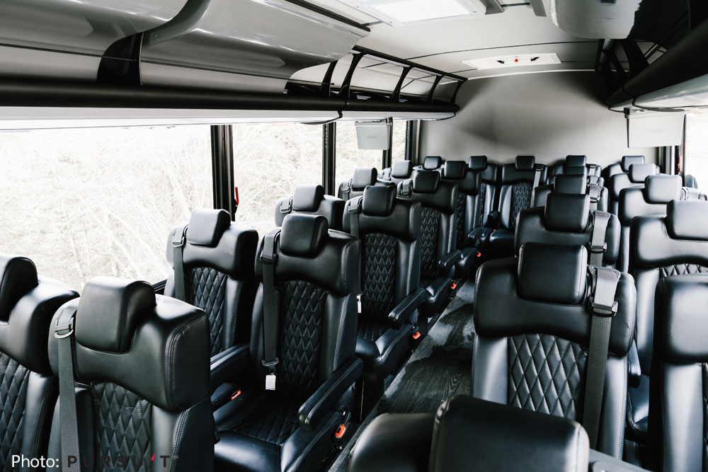 Spacious and comfortable leather passenger seats inside the Brewster Express shuttle bus with large viewing windows.